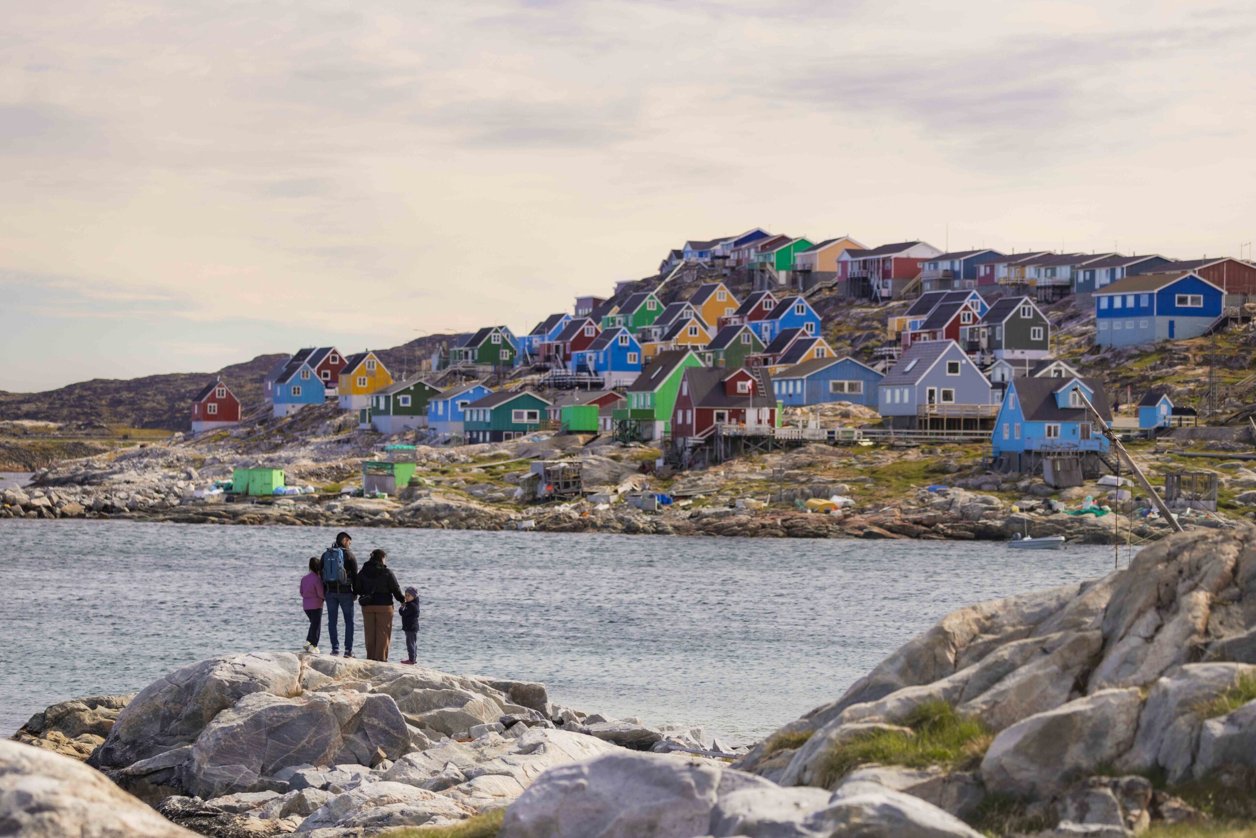 Disko Bay, a family views the colourful buildings in the distance