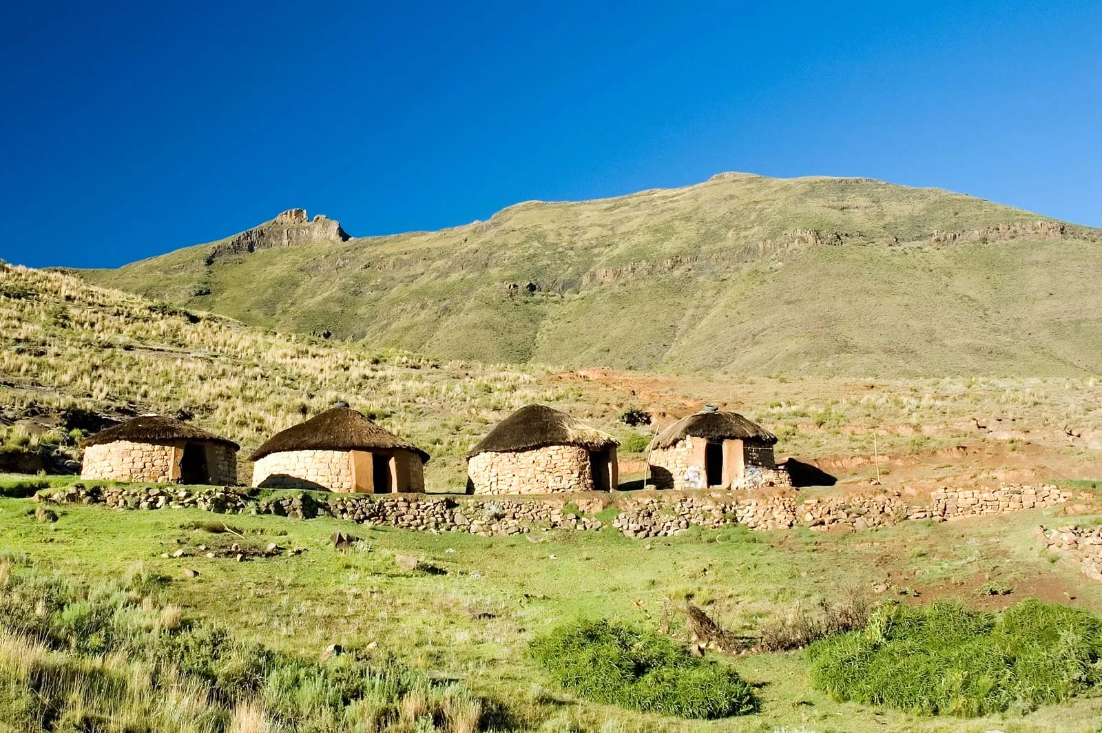 Traditional circular huts with thatched roofs and coloured door frames, Lesotho.