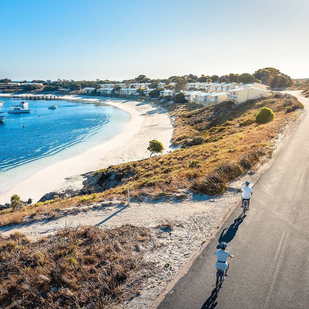 A couple bike riding by the ocean in Australia.